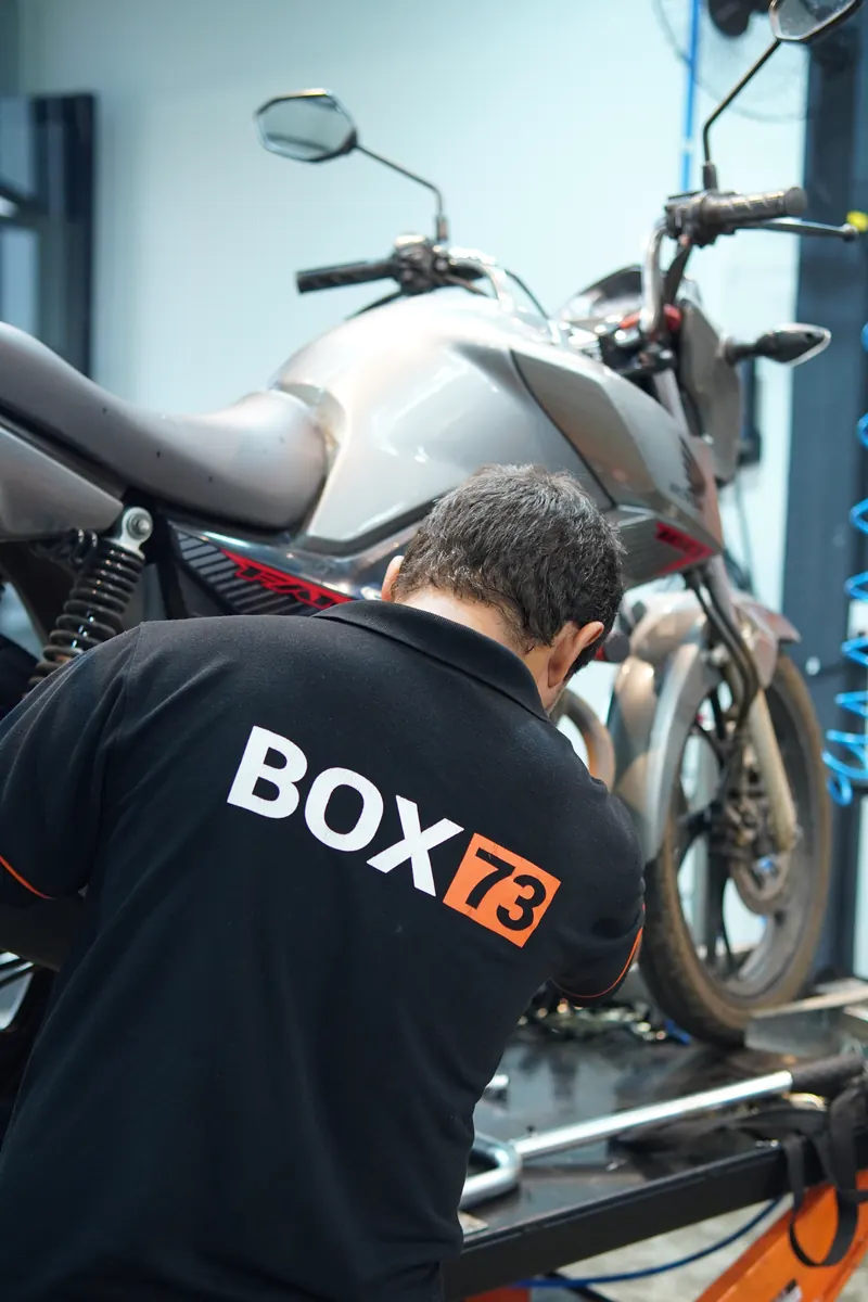 Mecânico com a camisa da Box 73 trabalhando em uma moto