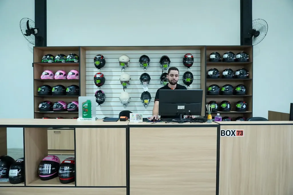 Balcão de atendimento da Box 73 com parede de capacetes